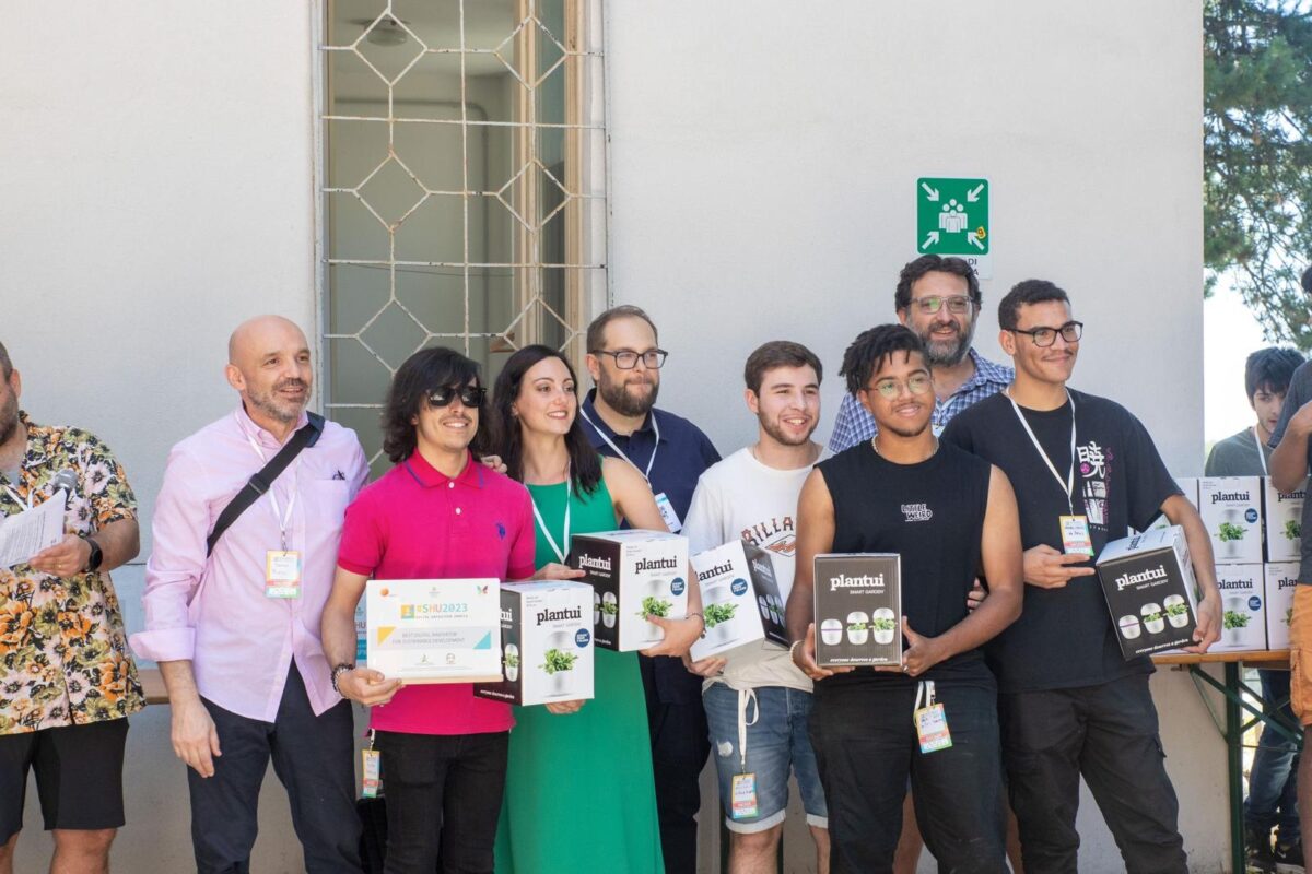 Foto scattata durante la premiazione del Social Hackathon Umbria 2023. Da sinistra verso destra, il team è composto da Matteo Piselli, Filippo Bistocchi e Vittoria Mancini di Mecenauta; Umberto Rosini, Vasco Manuel da Silva Duarte, Thiago Mateus da Cruz Santus, Pedro Kaleb de Jesus. In secondo piano, Altheo Valentini, fondatore di EGInA, uno degli organizzatori della manifestazione.